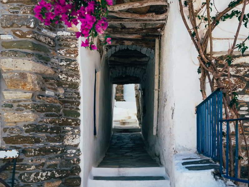 Streets of village on Tinos island with Cycladic houses and the Bougainvillea flowers tree, Cyclades, Greece