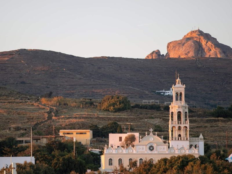Tinos island Chora town Cyclades Greece religious destination. Sunbeam colors Panagia Megalohari Orthodox Church and hill, nature around.